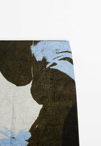 Gros plan sur un tissu avec un motif texturé abstrait bleu, marron et blanc cassé sur un fond blanc uni.