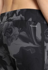 Black and gray athletic leggings with a glossy, marbled pattern. Features a zip pocket and the "Climacool" logo. Smooth texture.