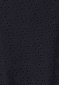 Sort stof med et gentaget blomster-øjet-lace-mønster med små, jævnt fordelte huller, der danner blomsterformer.