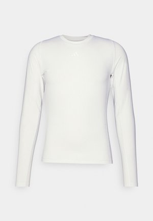 Maglietta sportiva a maniche lunghe di colore bianco, realizzata in materiale liscio e elasticizzato. Presenta un collo rotondo e un logo discreto sul petto.