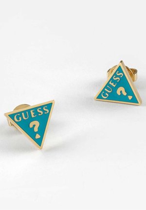 Paire de boucles d’oreilles clous triangulaires en or avec émail turquoise et le mot "GUESS" ainsi qu’un point d’interrogation en lettrage doré.