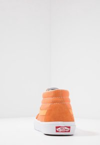 Baskets hautes en suède orange vif avec accents jaunes, semelle en caoutchouc blanche et col rembourré ; logo de la marque sur le talon.