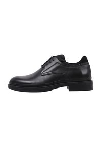 Chaussure habillée en cuir noir avec finition lisse, bout arrondi, design à lacets et détails de couture subtils. Elle dispose d'une semelle rembourrée.