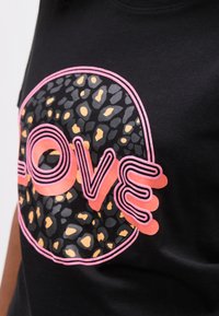 Μαύρο πουκάμισο με κυκλικό φόντο λεοπάρ και τη λέξη "LOVE" σε έντονα ροζ και κοραλλί στρωμένα γράμματα.