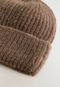 Eine braune gerippte Strickmütze liegt flach auf einem hellen Hintergrund und zeigt ihren strukturierten Stoff und ihre Wärme.