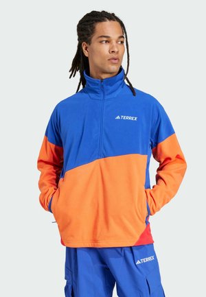 Pullover in pile blu e arancione, con colletto con zipper, maniche lunghe e logo in evidenza. Tessuto morbido con una vestibilità rilassata.