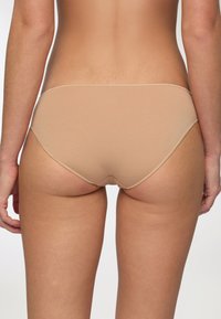 Slip invisibile color carne con una consistenza morbida e liscia e design minimalista. Presenta un taglio a vita bassa e dettagli di cucitura discreti.