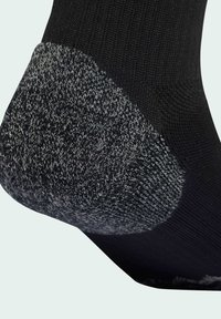 Sort sok med en grå, tekstureret hæl og let mønstrede detaljer. Har en glat krop og forstærket syning for holdbarhed.