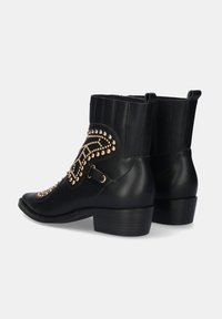 Botas negras de cuero hasta el tobillo con adornos de tachuelas, punta afilada y tacón bajo. Incluyen un detalle de correa lateral y un respaldo texturizado.