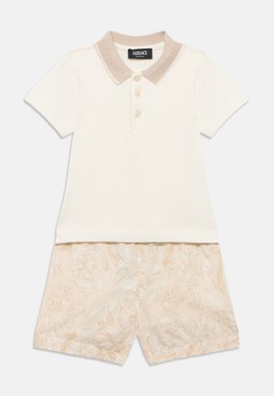 Polo shirt in cream, with a light beige textured collar and three buttons; paired with floral-patterned shorts in soft peach and beige hues.