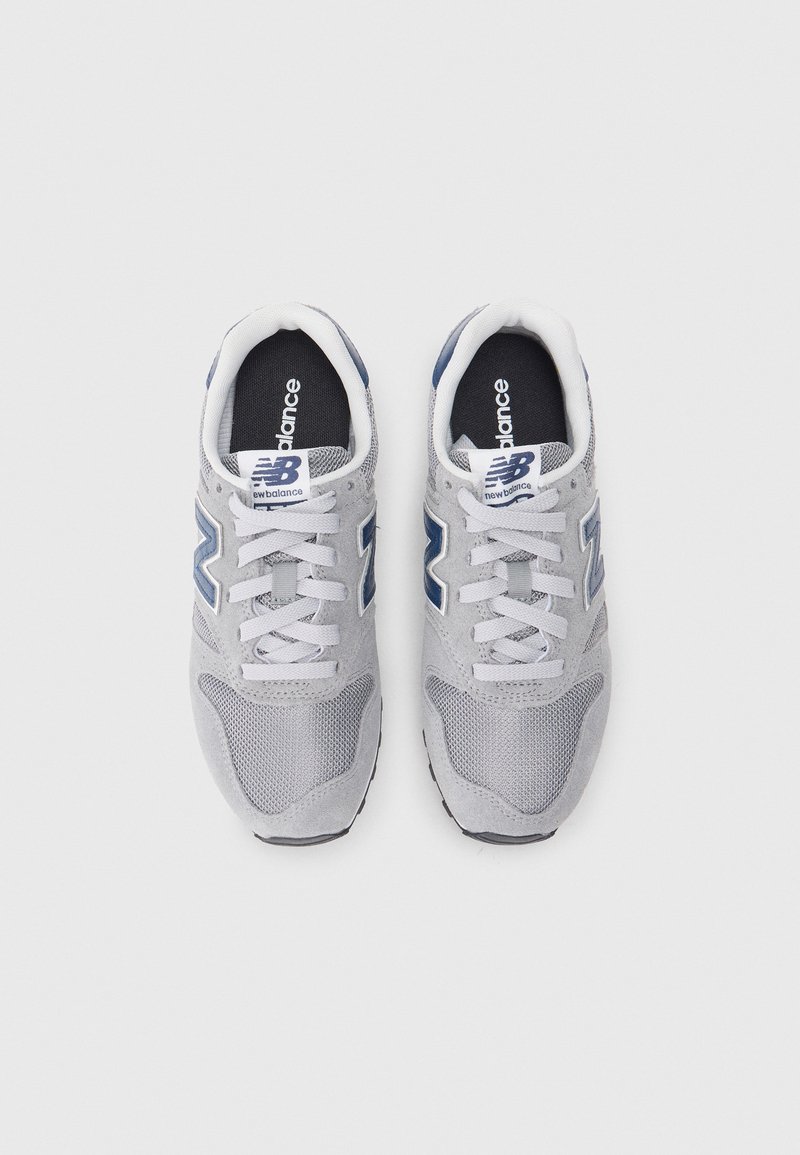 Baskets grises en maille et en daim, avec un design à lacets blancs, des accents bleu marine et une semelle texturée avec des détails de logo.