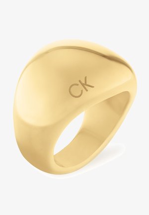 Gouden ring met een gladde, ronde vorm en het CK-logo. Het oppervlak is gepolijst en weerkaatst licht met een strakke textuur.