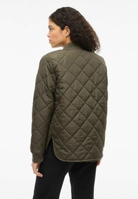 Oljčno zelena prešita jakna z gladko teksturo, z visokim ovratnikom, dolgimi rokavi in stranskimi razporki za boljšo gibljivost.