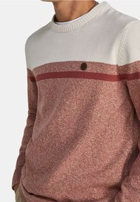 Gestrickter Pullover in Bordeauxrot und Creme mit Rundhalsausschnitt. Mit horizontalen Streifen und einem kleinen runden Logodetail auf der Brust.