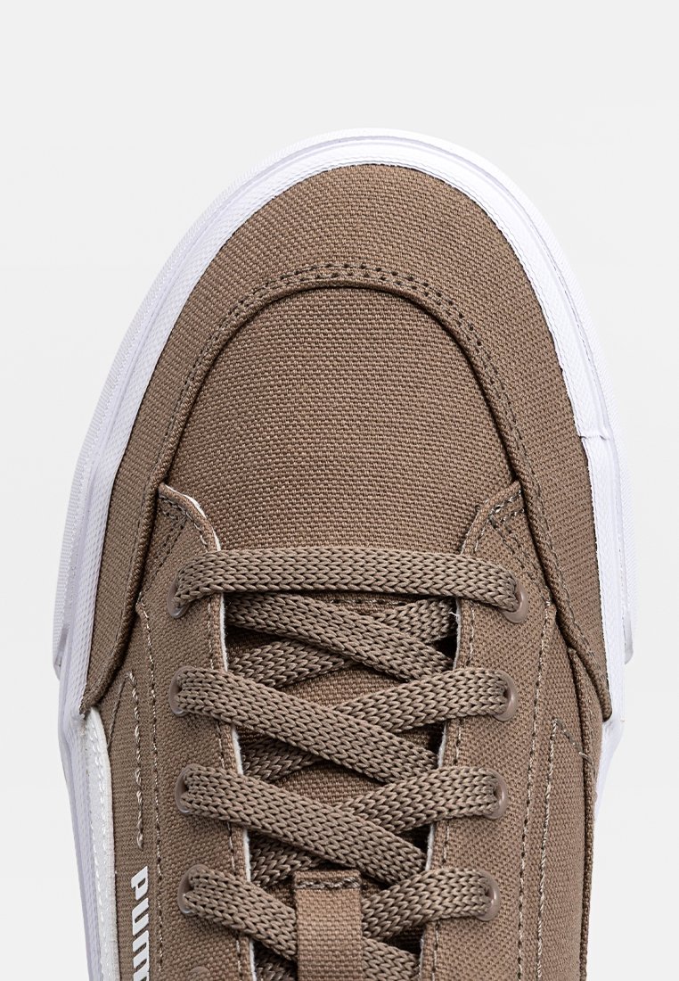 Zapatillas de lona marrón con suela de goma blanca. Presentan cordones redondos, acentos cosidos y un logotipo en el costado. Tejido texturizado para mayor agarre.