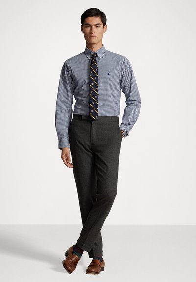 Heren blauw-witte geruite dress shirt met knoopkraag, gecombineerd met donkergrijze broek, bruine loafers en gestreepte sokken.