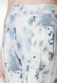 Floral-patterned leggings in soft, lightweight fabric featuring blue and green hues. Includes a subtle logo and a smooth texture.