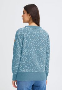 Felpa blu con motivo a fantasia, collo rotondo e polsini a coste, caratterizzata da piccole macchie chiare, realizzata in tessuto morbido.