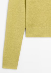 Pull à manches longues avec poignets en tricot vert olive clair, avec détail d'ourlet côtelé sur fond blanc.