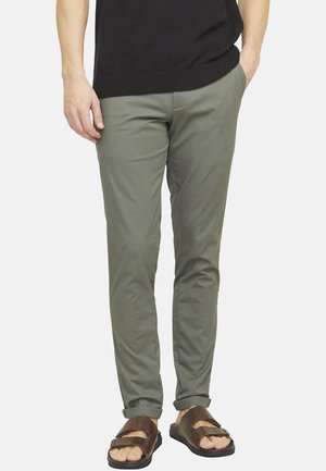 Chinos slim fit kaki en tissu léger, avec un front plat, des poches latérales et des ourlets roulés, associés à des sandales brunes.