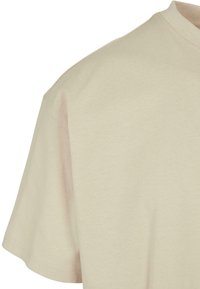Beige bomull t-skjorte med rund hals og korte ermer, med en jevn tekstur og lett avslappet passform.