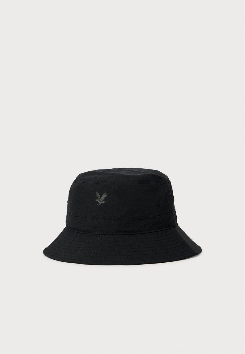 Schwarzer Bucket Hat mit breiter Krempe und kleinem dunklem Adlerlogo auf der Vorderseite, vor einem schlichten hellen Hintergrund.