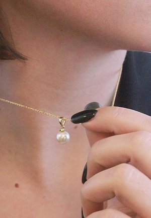 Collana d'oro con pendente a perla, con una superficie liscia e una catena delicata. La perla è rotonda, bianca e sospesa da un montaggio a griffe.