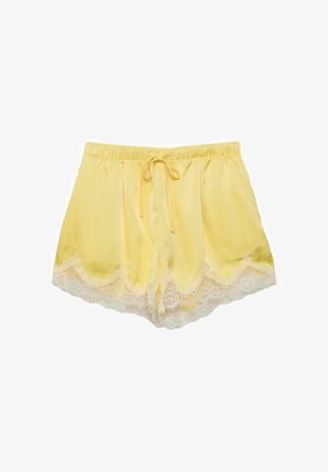 Žlté saténové šortky s bielou čipkou na leme a elastickým pásom viazaným na šnúrku vpredu.