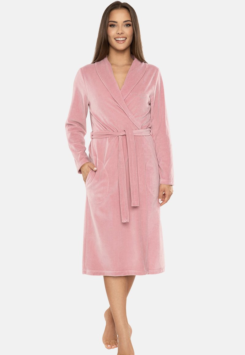 Accappatoio in velluto rosa con cintura, maniche lunghe e tasche. Il design presenta un colletto a scialle e una lunghezza a metà polpaccio. Texture morbida.