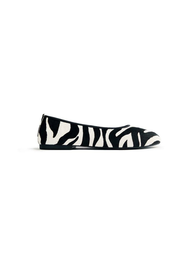 Zapatos planos en blanco y negro con diseño de impresión de cebra, hechos de tela texturizada, con punta redondeada y suela de perfil bajo.
