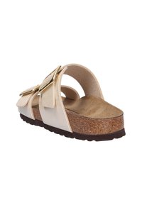 Sandalia con plantilla de corcho, detalle de tira metálica dorada y suela plana. Color beige claro con textura suave y hebilla ajustable.