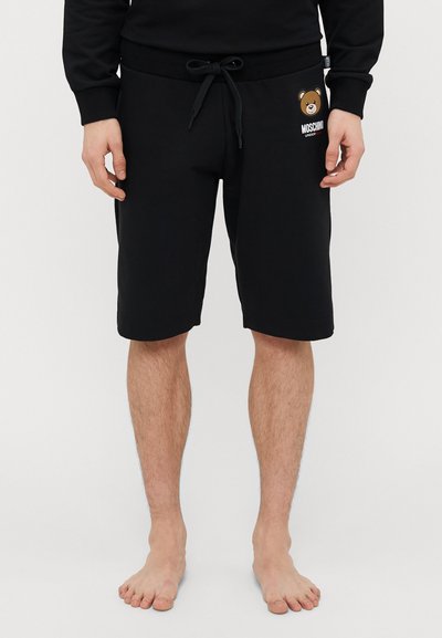 Sorte bomulds shorts med elastisk talje og snor, prydet med en brun bjørn grafisk illustration og "Moschino" tekst på venstre ben.