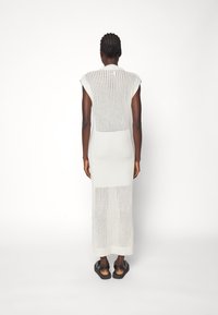 Lichtgrijze gebreide maxi-jurk met korte mouwen, voorzien van een patroon op de rug en zijsnedes. Doorlopend gestructureerde geribbelde stof.