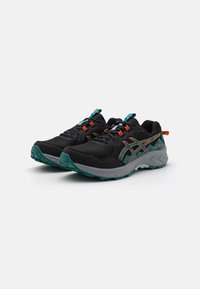 Chaussures de sport noires avec tige en mesh, accents teal et orange, semelle extérieure texturée et col rembourré pour le confort. Détails réfléchissants sur les lacets.