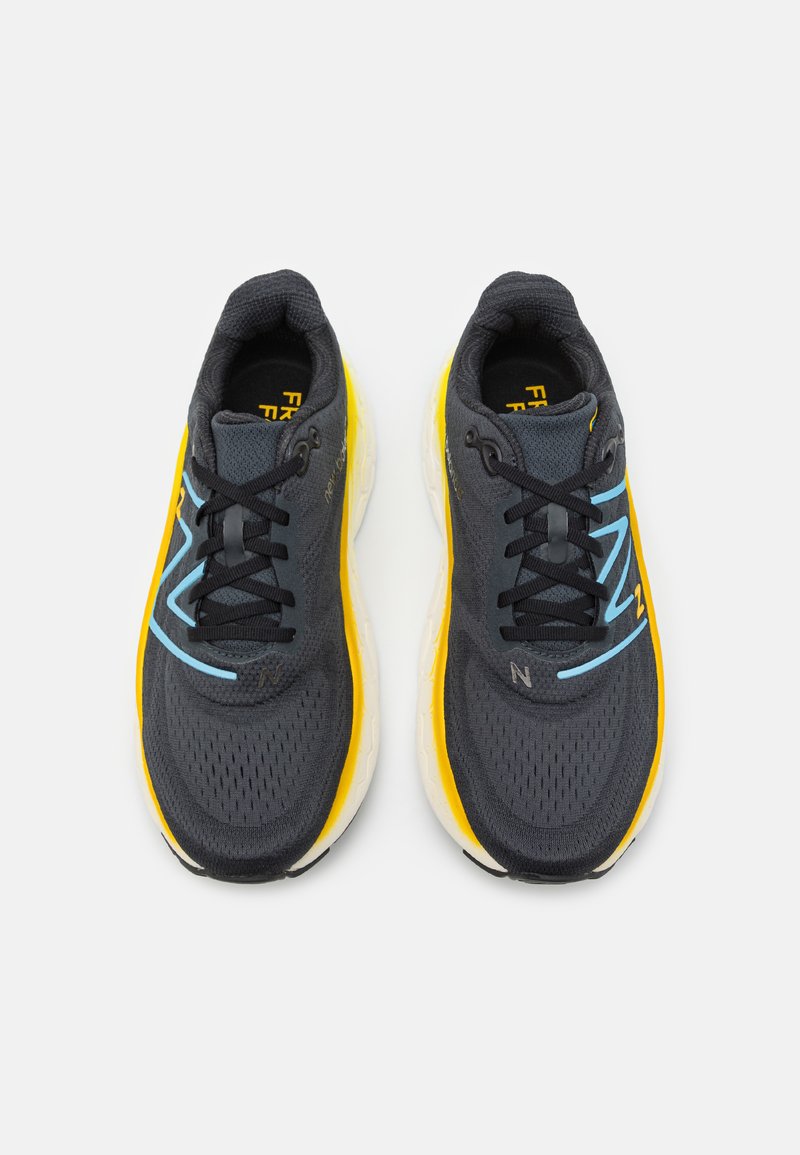 Sneaker nere in rete con design arrotondato, dotate di una suola gialla brillante e dettagli azzurri chiari sui lati e nei lacci.