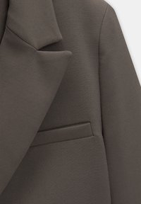 Donkergrijze blazer met een gladde textuur, met een ingesneden revers en een enkele borstzak. Tailored ontwerp, met strakke lijnen en een gestructureerde vorm.