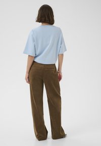 Svetlomodrý krátky rukáv top s uvoľneným strihom, doplnený hnedými kordovými kalhotami s širokými nohavicami. Hladká látka s jemnou textúrou a dvoma zadnými vreckami.