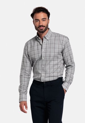 Grijs geruit overhemd met donkere accenten, van katoen, met lange mouwen. In combinatie met donkere broek staat het model tegen een neutrale achtergrond.