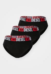 Culottes pour femmes noires avec une large ceinture élastique rouge et blanche ornée du logo "DIESEL". Trois paires présentées dans un agencement empilé.