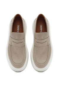 Beige suede slip-on shoes with a notched strap and white rubber sole. Smooth texture with minimal stitching detail. Brand name visible inside.