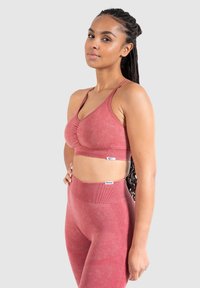 Rode sport-bh met geplooide voorkant, verstelbare banden, gecombineerd met high-waisted leggings met een textuurpatroon en geribbelde accenten.