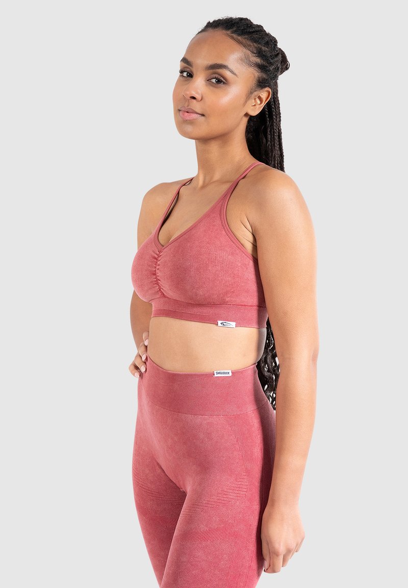Rode sport-bh met geplooide voorkant, verstelbare banden, gecombineerd met high-waisted leggings met een textuurpatroon en geribbelde accenten.