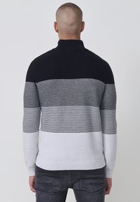 Herrenpullover mit hochgeschlossenem Kragen, farblich abgesetzt in Marineblau, Grau und Weiß mit horizontalen Streifenmustern. Weiche Stricktextur.
