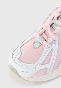 Rosa mesh sneakers med hvite syntetiske overlegg, rund tå, reflekterende sølvdetaljer og tynne rosa snøringer. Teksturert gummisåle synlig.