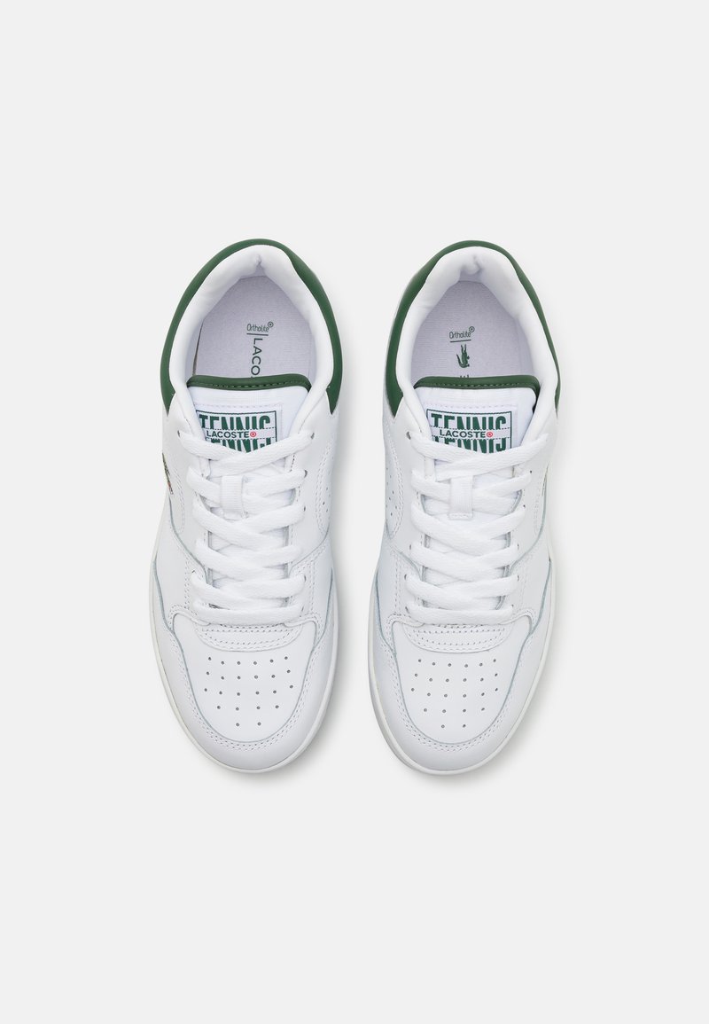 Witte leren sneakers met groene accenten, geperforeerde neus en platte witte veters. Bevat Lacoste-branding op de tong en zijkant.