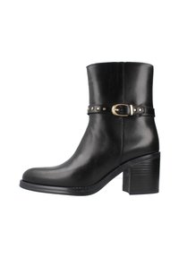 Botín de cuero negro hasta el tobillo con punta redonda, tacón medio y una correa decorativa con herrajes dorados y acentos de tachuelas.