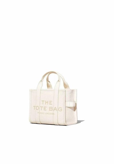 Kangas kassi ivories, millel on reljeefne tekst "THE TOTE BAG" ja "MARC JACOBS." Omab lühikesi käepidemeid ja õmblusaksente. Kompaktne disain.