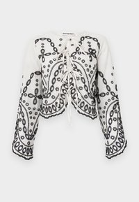 White cropped top with black embroidered floral and paisley patterns. Features a rounded neckline and flowing long sleeves with scalloped edges.