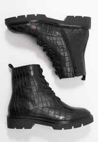Bottines noires en simili cuir texturé avec un motif crocodile, dotées d'une fermeture éclair sur le côté et d'une semelle en caoutchouc robuste.