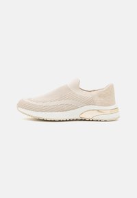Slip-on-sneaker i ljusbeige stickat tyg, med texturerade mönster, vit gummisula och en metallisk guldaccent på hälen.